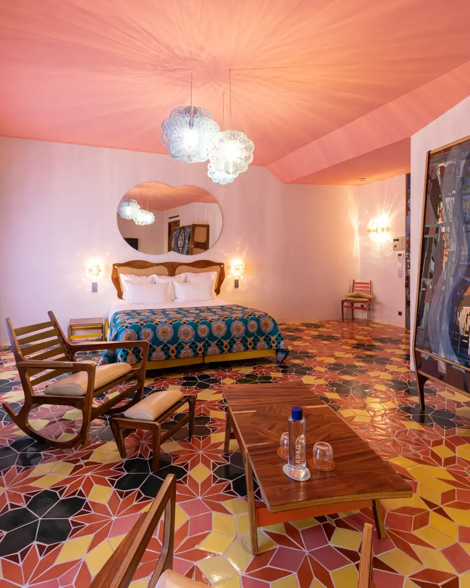 Pink room at L'Arlatan with a coffee table, two armchairs and a bed in the background